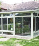 <p>This three season studio sunroom features glass kneewall windows and a roof that is shingled to match the house.</p>
